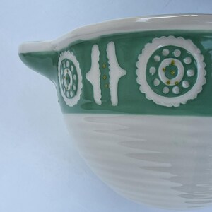 Peut inclure: Un bol en c&eacute;ramique blanc et vert avec une anse. Le bol pr&eacute;sente une bande d&eacute;corative verte avec des accents blancs et dor&eacute;s. La partie inf&eacute;rieure du bol est blanche avec un motif textur&eacute; et nervur&eacute;.
