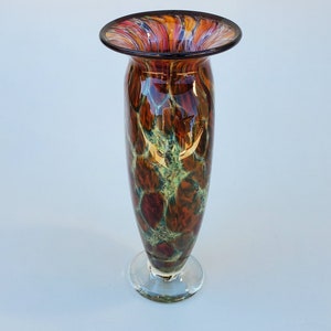 May include: A tall, brown glass vase with a wide mouth and a clear glass base. The vase has a mottled pattern of brown, orange, and green.