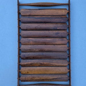 May include: A vintage wooden tray with a slatted design, featuring a series of horizontal wooden slats held together by vertical supports. The tray has a dark brown finish and a handle at each end. The background is a solid light blue.
