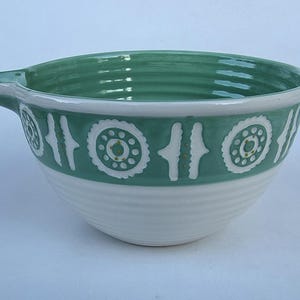 Peut inclure: Un saladier en c&eacute;ramique avec un bord vert et une bande d&eacute;corative. Le bol a une base blanche et un bec verseur. La bande verte pr&eacute;sente des motifs g&eacute;om&eacute;triques blancs. Le bol est con&ccedil;u pour la cuisine.