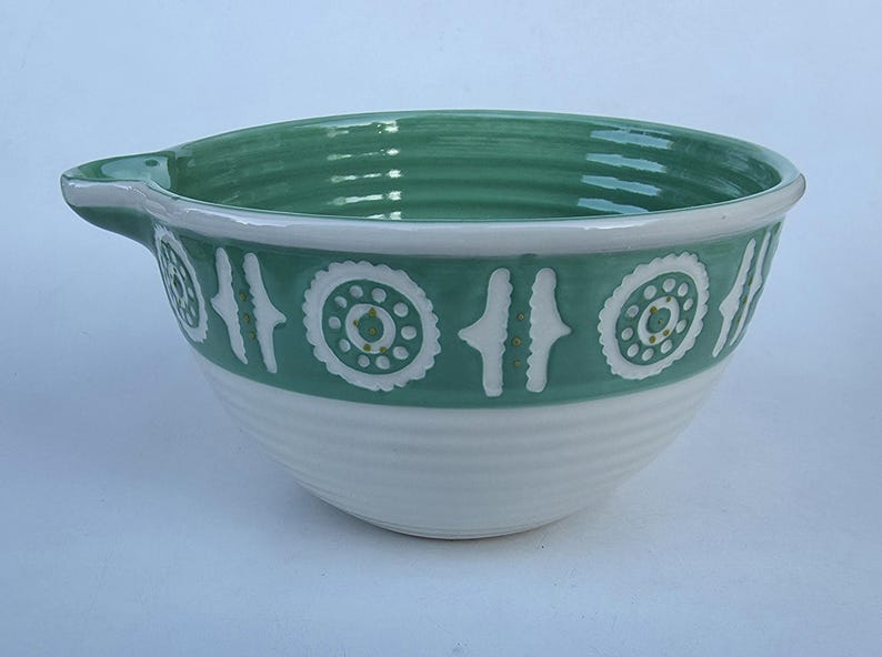 Peut inclure: Un saladier en c&eacute;ramique avec un bord vert et une bande d&eacute;corative. Le bol a une base blanche et un bec verseur. La bande verte pr&eacute;sente des motifs g&eacute;om&eacute;triques blancs. Le bol est con&ccedil;u pour la cuisine.