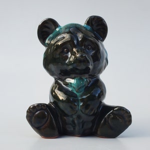 May include: A black and green ceramic bear figurine with a glossy finish. The bear is sitting with its legs crossed and has a small, round nose.