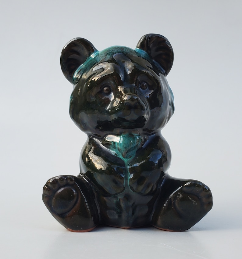 May include: A black and green ceramic bear figurine with a glossy finish. The bear is sitting with its legs crossed and has a small, round nose.