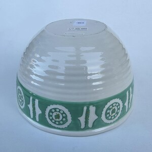 Peut inclure: Un bol en c&eacute;ramique blanc avec une bande verte orn&eacute;e d'un motif floral stylis&eacute; r&eacute;p&eacute;t&eacute;. Le bol a une texture c&ocirc;tel&eacute;e et une forme arrondie, adapt&eacute; au service ou &agrave; l'exposition.