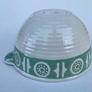 Peut inclure: Un saladier en c&eacute;ramique blanc et vert. Le bol a une forme large et arrondie avec un ext&eacute;rieur textur&eacute;. Une bande verte avec un motif r&eacute;p&eacute;titif de motifs floraux blancs entoure le bol. Une petite poign&eacute;e est sur le c&ocirc;t&eacute;.