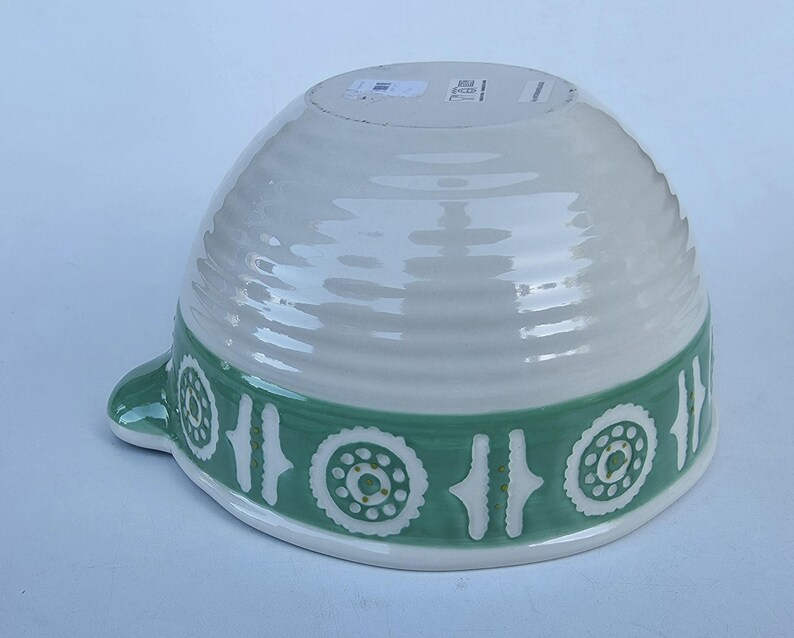 Peut inclure: Un saladier en c&eacute;ramique blanc et vert. Le bol a une forme large et arrondie avec un ext&eacute;rieur textur&eacute;. Une bande verte avec un motif r&eacute;p&eacute;titif de motifs floraux blancs entoure le bol. Une petite poign&eacute;e est sur le c&ocirc;t&eacute;.