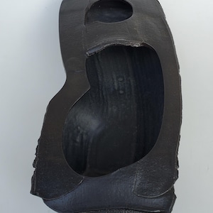 May include: A black rubber tire with a large hole in the center. The tire is worn and has a rough texture.