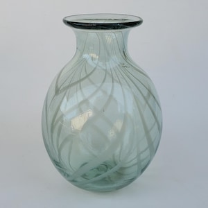 May include: A clear glass vase with a light green tint and white swirling lines throughout the body.