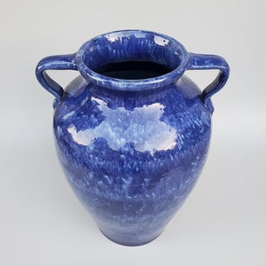 Op de afbeelding: Een grote, blauwe keramische vaas met twee handvatten. De vaas heeft een gevlekt blauwe glazuur met witte strepen.