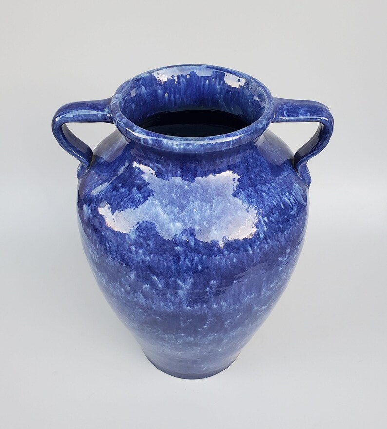 Op de afbeelding: Een grote, blauwe keramische vaas met twee handvatten. De vaas heeft een gevlekt blauwe glazuur met witte strepen.