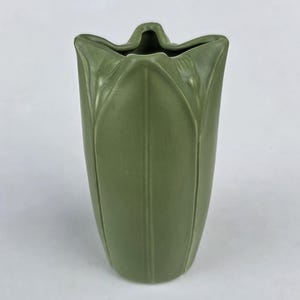 May include: A matte sage green ceramic vase with a tulip-like shape. The vessel features vertical raised ridges that extend from the base to the scalloped, petal-shaped rim, creating a structured, organic silhouette with a smooth finish.