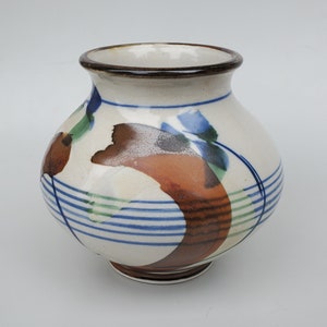 May include: A white ceramic vase with a brown rim and a blue, green, and brown abstract design.