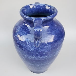 Op de afbeelding: Een grote blauwe keramische vaas met twee handvatten. De vaas heeft een gevlekt blauw glazuur met een wit marmereffect.
