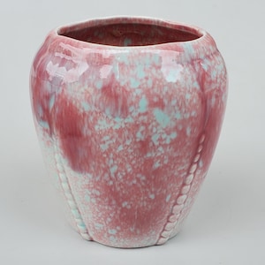 May include: A pink and blue ceramic planter with a textured surface and a beaded rim.