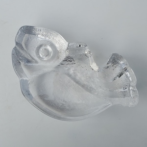 May include: A clear glass fish shaped dish. The dish is made of glass and has a smooth, rounded surface.