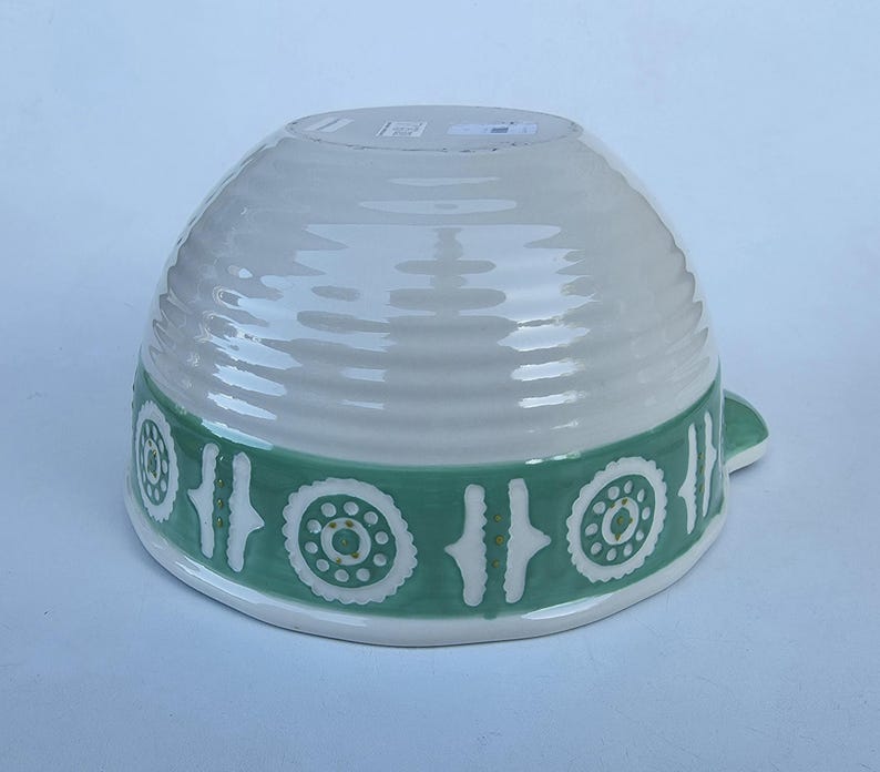 Peut inclure: Un bol en c&eacute;ramique blanc avec une bande vert clair orn&eacute;e d'un motif r&eacute;p&eacute;titif de cercles et de lignes. Le bol a une texture c&ocirc;tel&eacute;e et une petite poign&eacute;e. Le design est simple et &eacute;l&eacute;gant.