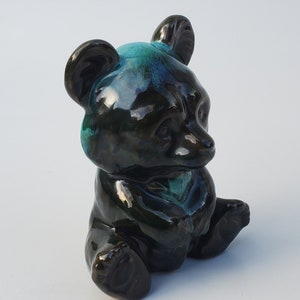 May include: A ceramic black bear figurine with a teal glaze. The bear is sitting with its paws crossed and has a glossy finish.
