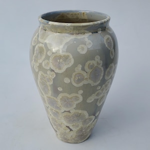 May include: A ceramic vase with a light gray glaze and a white and light purple speckled pattern.