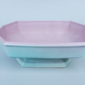 May include: A light blue and purple ceramic serving bowl with a scalloped edge and a pedestal base.
