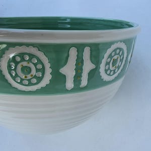 Peut inclure: Un bol en c&eacute;ramique blanc et vert. La partie sup&eacute;rieure est verte avec des motifs d&eacute;coratifs blancs. La partie inf&eacute;rieure est blanche avec des rainures horizontales. Le bol est de forme arrondie.