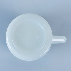 May include: White ceramic mug with a handle. The mug is plain white with no design or markings.