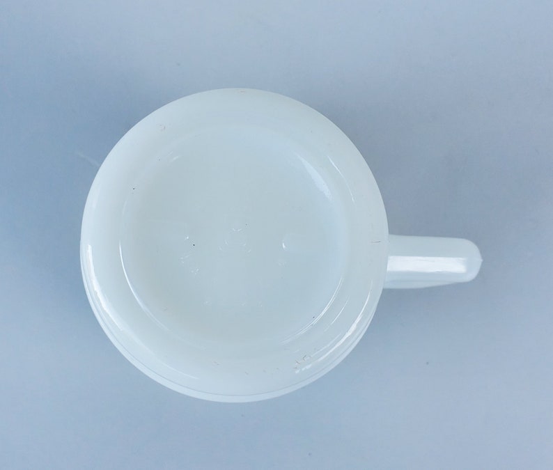 May include: White ceramic mug with a handle. The mug is plain white with no design or markings.