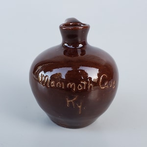 May include: A brown ceramic jug with a handle and the words "Mammoth Cave KY." inscribed on the side.