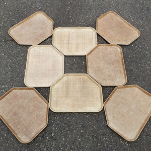 May include: Eight woven trays in a variety of sizes and shapes, arranged in a circular pattern on a gray surface.