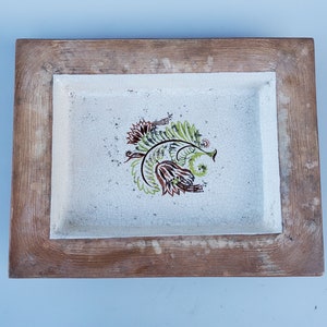 May include: A wooden tray with a white ceramic insert featuring a brown, green, and white floral design. The tray has a distressed wood finish.