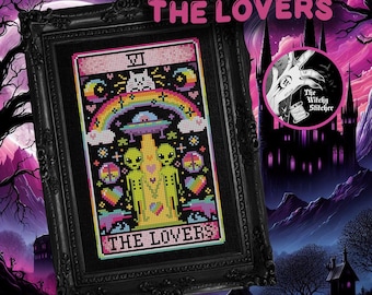 May include: A framed cross-stitch art piece titled THE LOVERS, featuring two green aliens standing under a UFO and a rainbow. The design includes hearts, peace signs, and a cat head, all rendered in vibrant colors against a black background.