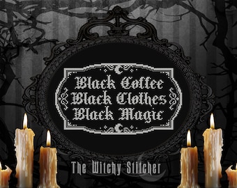 Op de afbeelding: Een zwart-witte kruissteekontwerp in een zwart, versierd frame met de tekst "Black Coffee Black Clothes Black Magic" en de woorden "The Witchy Stitcher" onder het ontwerp. Het ontwerp is omringd door zes brandende kaarsen.