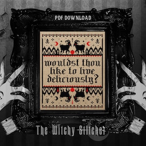May include: A framed cross-stitch design with the text "wouldst thou like to live deliciously?" in gothic lettering. The design features black goats, moons, and stars on a tan background, framed in black. The image is held by illustrated hands.