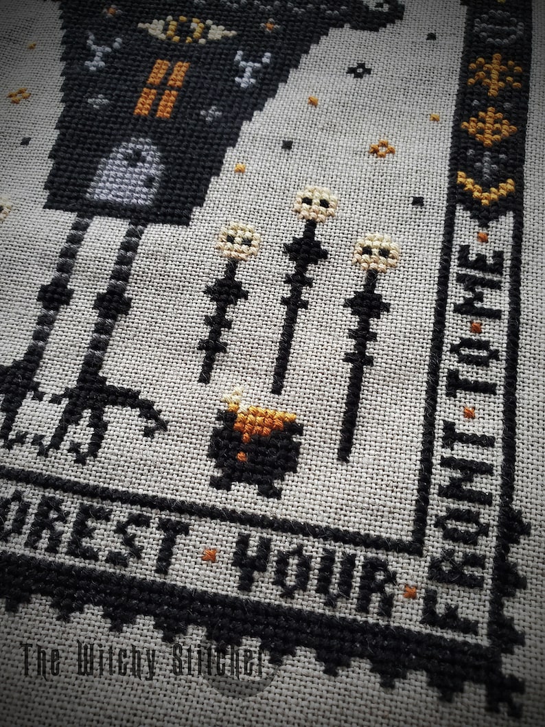 May include: Black and white cross-stitch embroidery of a witch with a cauldron and the text "Forest Your Time".