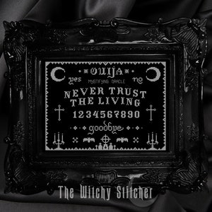 Puede incluir: Una imagen enmarcada en negro con un dise&ntilde;o de tablero de Ouija bordado en blanco. El tablero presenta las letras del alfabeto, los n&uacute;meros del 1 al 10, y las palabras "s&iacute;", "no", "adi&oacute;s", y "NUNCA CONFIES EN LOS VIVOS".