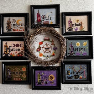 May include: Eight framed cross-stitch embroideries arranged around a central twig wreath. Each piece features a seasonal theme with text including Samhain, Yule, Imbolc, Mabon, Ostara, Lammas, Litha, and Beltane, accompanied by candles and symbols.