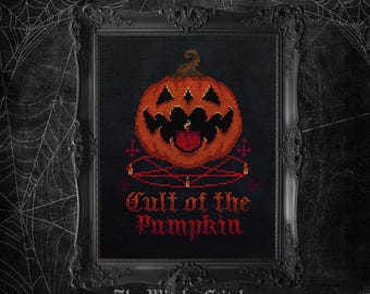May include: A cross-stitch embroidery in a black ornate frame featuring an orange jack-o'-lantern with a jagged black mouth and tongue, positioned above a red pentagram with small candles, and the text Cult of the Pumpkin in red.