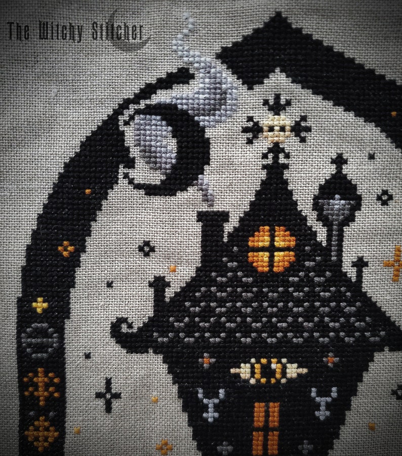 May include: Cross stitch pattern of a black and gray haunted house with orange windows and a crescent moon in the background. The text "The Wilky Stitcher" is in the top left corner.