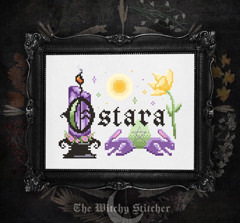 May include: A cross-stitch pattern in a black frame featuring the text Ostara in black gothic lettering. The design includes a purple candle, a yellow flower, a pale green egg with a pentagram, and two purple rabbits under a yellow sun.