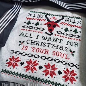 May include: White cross-stitch pattern with a red and black devil head, green trees, and the text "All I want for Christmas is your soul".