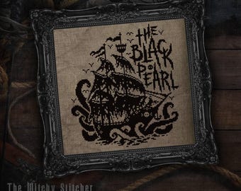 May include: A cross-stitch embroidery featuring a black ship and a giant octopus on tan fabric, framed in an ornate black frame. The text reads THE BLACK PEARL, accompanied by small bird silhouettes and a skull icon on the ship's hull.
