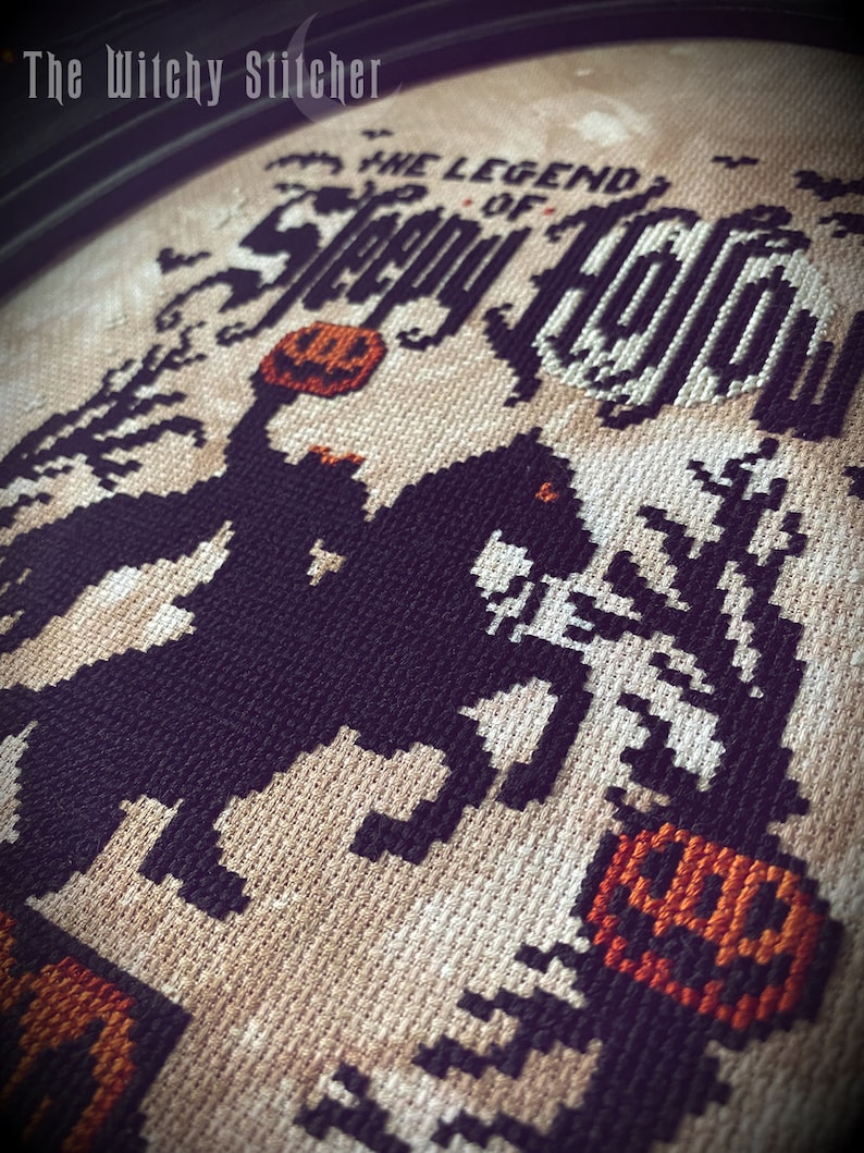 May include: Cross-stitch embroidery of the legend of Sleepy Hollow, featuring a black and white silhouette of the Headless Horseman riding a horse, holding a jack-o-lantern. The background is beige with the text "The Legend of Sleepy Hollow" in black.