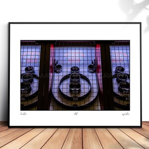 May include: A framed print of a vintage Skee-Ball arcade game. The game features numbered targets and ball return lanes. The print is displayed on a wooden surface.