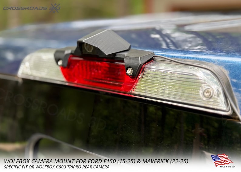 以下が含まれることがあります： 青いフォードF150トラックに取り付けられた黒いWolfboxカメラマウント。マウントは赤いブレーキライトの上に配置され、「WOLFBOX CAMERA MOUNT FOR FORD F150 (15-25) & MAVERICK (22-25)」というテキストが含まれています。