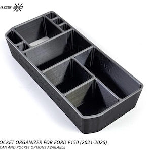 May include: A black console pocket organiser for a Ford F150 (2021-2025). The organiser has multiple compartments of varying sizes. The text "CROSSROADS EXO" is visible on the top left. The text "CONSOLE POCKET ORGANIZER FOR FORD F150 (2021-2025) ENERGY DRINK CAN AND POCKET OPTIONS AVAILABLE" is at the bottom.
