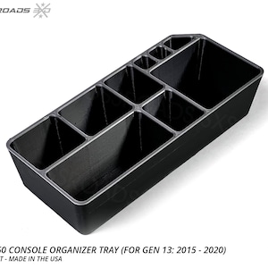 May include: Black console organizer tray for a Ford F-150 truck. The tray has multiple compartments of varying sizes to store items. The text "FORD F-150 CONSOLE ORGANIZER TRAY" is visible. Made in the USA.