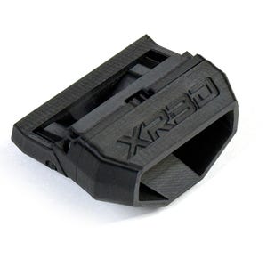May include: A black, rectangular object with the text "XR3D" embossed on its surface. The object has a textured appearance and a hollow, open section on one side. It appears to be made of a rigid material.