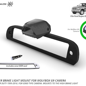 May include: Black Ford center brake light mount for Wolfbox G9 camera. Fits Ford Super Duty 1999-2016. Includes new OEM seal. The image also shows a truck and a camera.