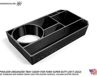 Op de afbeelding: Zwarte bekerhouder organizer tray caddy voor Ford Super Duty trucks. De caddy heeft meerdere compartimenten, waaronder een grote ronde bekerhouder en verschillende rechthoekige secties. De tekst op de afbeelding luidt "CUPHOLDER ORGANIZER TRAY CADDY FOR FORD SUPER DUTY (2017-2022)".