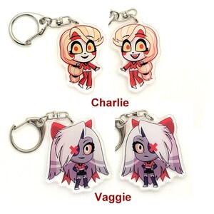Puede incluir: Dos juegos de llaveros con personajes de dibujos animados de la serie animada "Hazbin Hotel". El primer juego presenta a Charlie, un personaje de cabello rojo con un vestido rojo y botas blancas. El segundo juego presenta a Vaggie, un personaje de cabello morado con un atuendo rojo y negro y botas blancas. Ambos juegos tienen llaveros plateados.