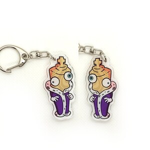 May include: Two purple and gold chess piece keychain charms with a crown and a face. The charms are attached to silver keychains.